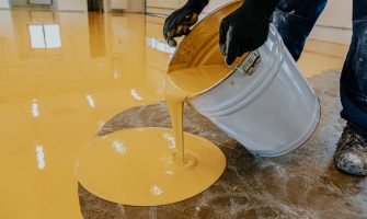 A construction worker apply epoxy resin in an industrial hall