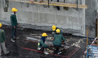 Aerial view of busy industrial construction site workers with cranes working. Top view of development high rise architecture building at noon.
