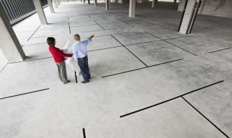 Asian architect with caucasian woman planning workspaces in a new raw office location